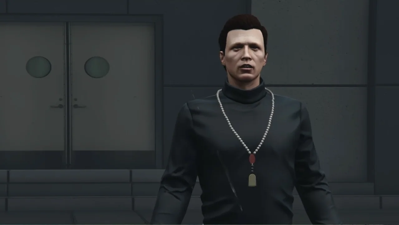 Grand Theft Hamlet (2024) movie still: medium — A dark gray building exterior features a set of double doors with circular windows. A man in a dark…