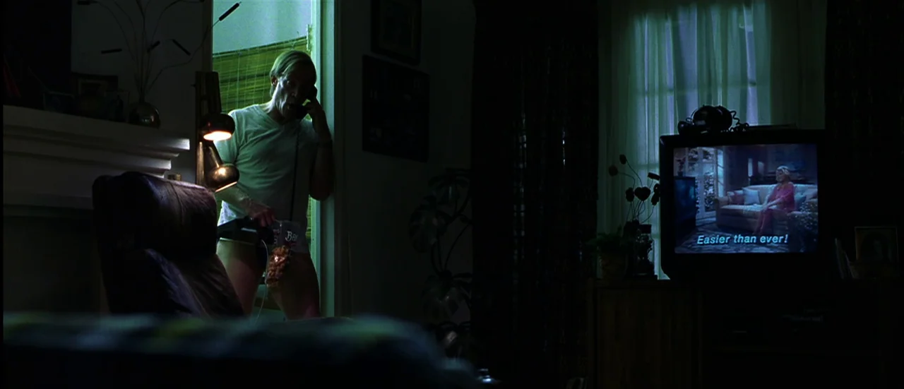 The Mexican (2001) movie still: medium — A dimly lit room features a man standing in a doorway during the night. The man holds a telephone and a bag…