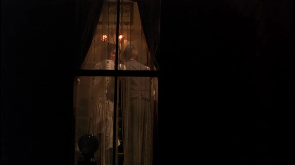 Days Of Heaven (1978) movie still: medium — A night exterior view of a building illuminated only from within a window. Two people stand close…