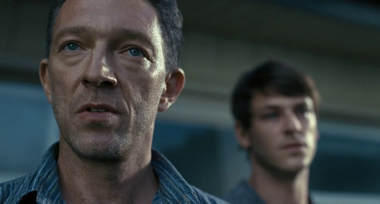 It’s Only The End Of The World (2016) movie still: medium — Two men stand outdoors in an overcast urban area with a building in background. The man…