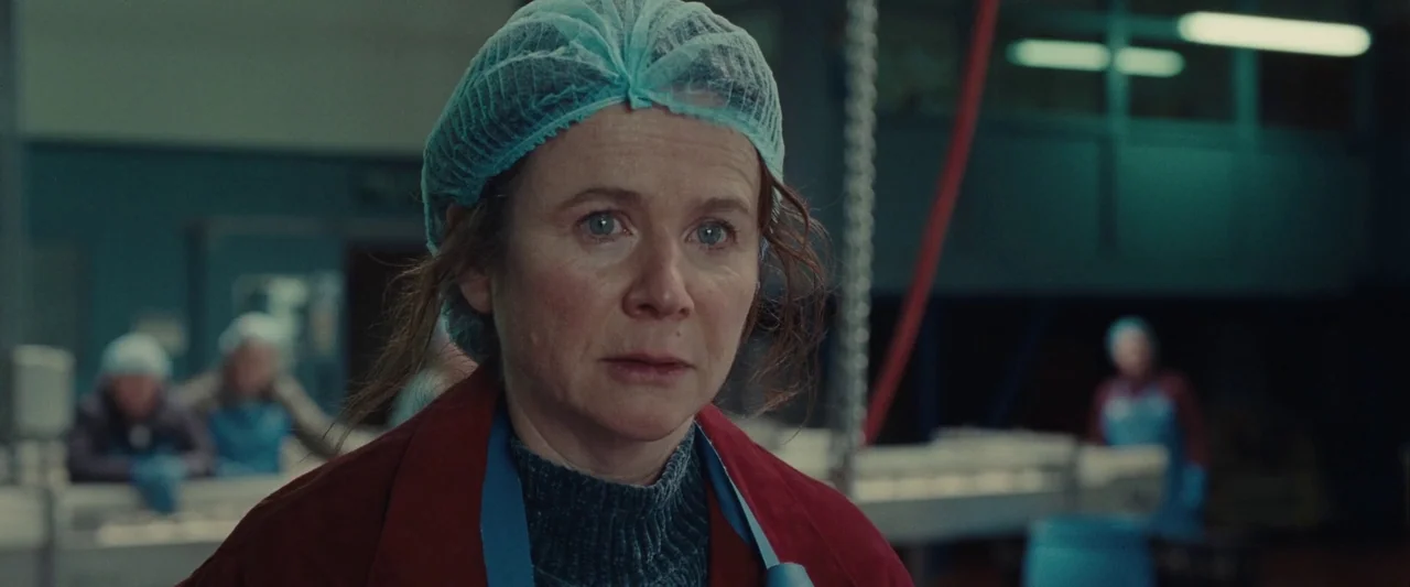 God’s Creatures (2022) movie still: closeup — A food processing area with industrial machinery and blue plastic components in the background. A…