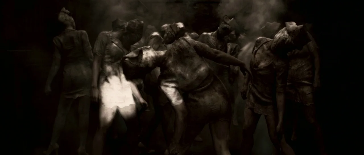 Silent Hill movie still: wide — A dark, smoke-filled corridor in a dilapidated medical facility houses multiple identical figures. The figures are…