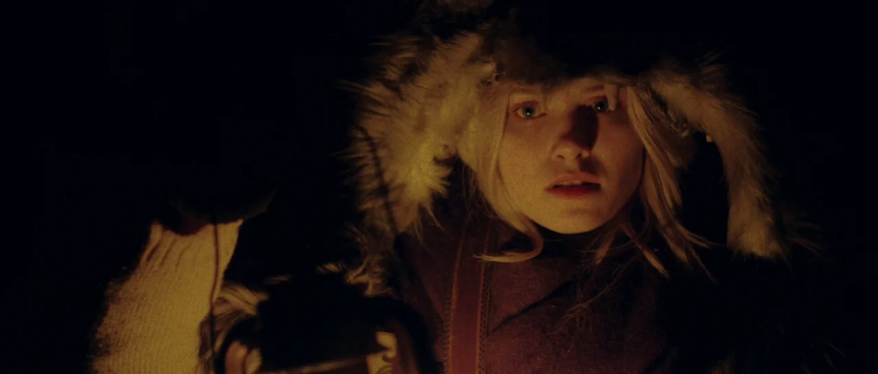Starfish (2018) movie still: closeup — A dark, underexposed outdoor environment is entirely black save for a central subject. A young woman with…
