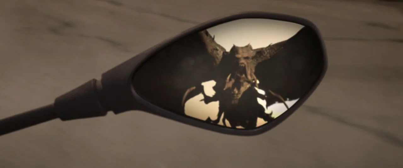 Resident Evil: The Final Chapter (2016) movie still: closeup — A close-up view of a black motorcycle side mirror reflecting a distant landscape. A…