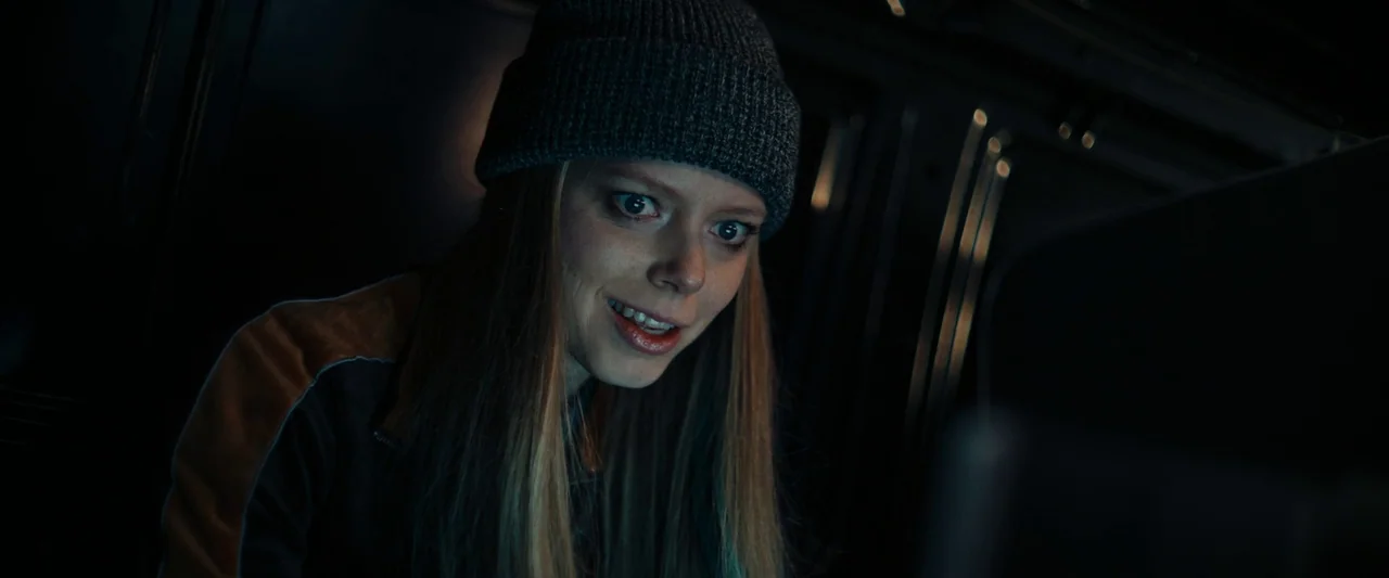 We Are Zombies (2023) movie still: closeup — A dark, cramped interior of a vehicle at night with metallic structural ribs visible. A young woman…