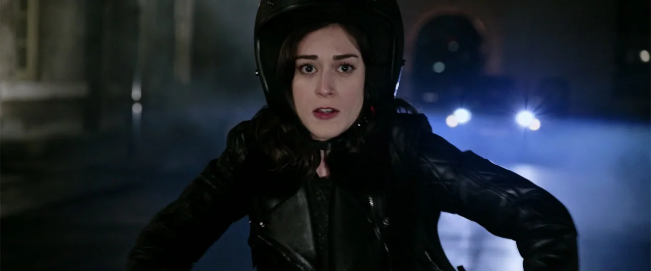 Now You See Me 2 (2016) movie still: medium — A woman wears a motorcycle helmet and black leather jacket while riding at night. Bright headlights…