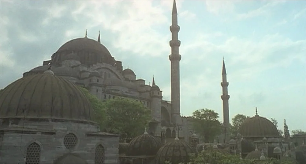 Footprints (Le Orme) (1975) movie still: establishing — A grand stone mosque with multiple domes and slender minarets rises against a cloudy sky.…