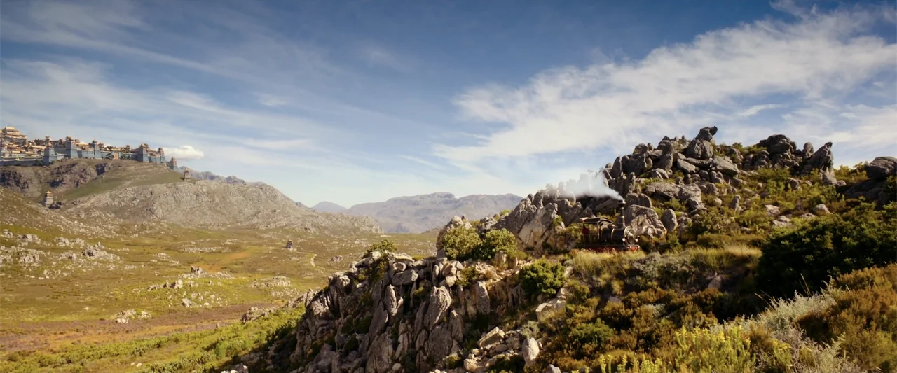 Jim Button and Luke the Engine Driver (2018) movie still: wide — A vast, sunlit landscape features craggy rock formations and distant tiered…