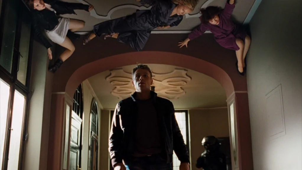 We Are The Night (2010) movie still: fullbody — A spacious hallway features arched doorways and high ceilings with decorative plaster molding. One…