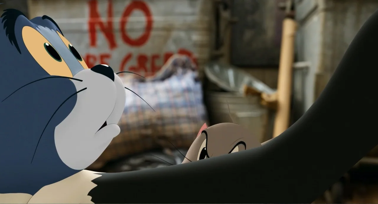 Tom & Jerry (2021) movie still: closeup — A cluttered exterior alleyway features a painted wall with graffiti in the background. A large cat…