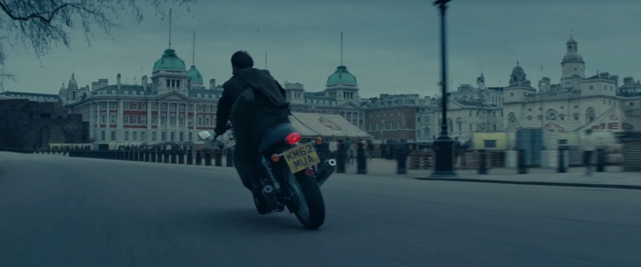 Edge of Tomorrow (2014) movie still: wide — A historic stone plaza surrounded by large, ornate government buildings in London. A person on a…