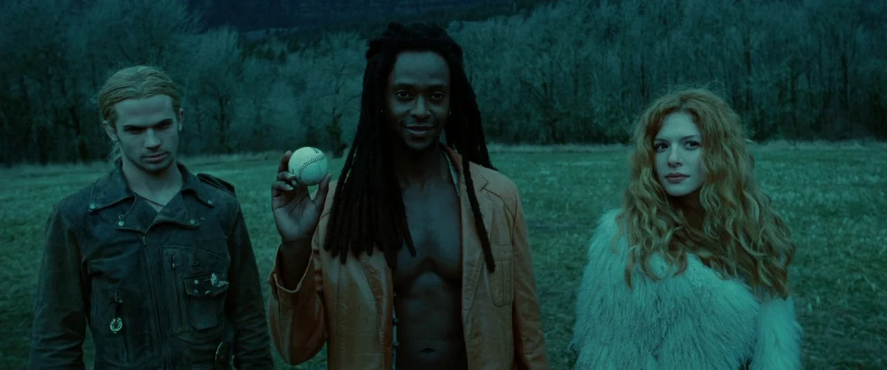 Twilight (2008) movie still: medium — Three individuals stand in an open field against a backdrop of leafless trees. The central male character…