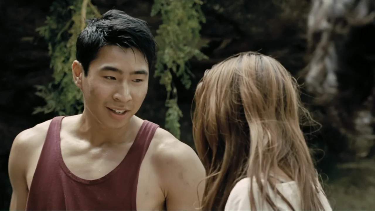 Tomorrow, When the War Began (2010) movie still: medium — A man stands in front of a woman in a wooded area with trees. The man is looking at the…
