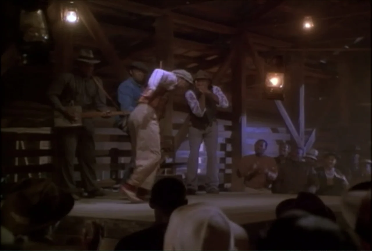 Miss Evers' Boys (1997) movie still: medium — A rustic barn interior features wooden beams and hanging lanterns in the dimly lit space. Musicians…