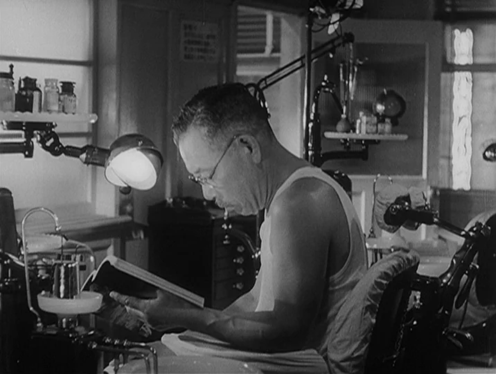 I Live In Fear (1955) movie still: medium — A compact dental workspace contains a reclining chair, medical equipment, and glass bottles. An older…