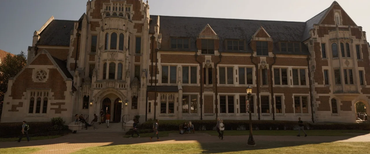 Life of the Party (2018) movie still: establishing — A collegiate gothic style brick building features stone trim and arched entrance doors. Several…