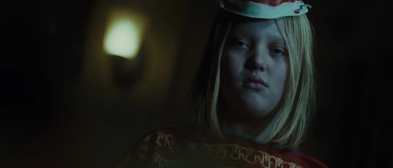 Halloween (2007) movie still: closeup — A child stands in a dark, dimly lit corridor during the night. The subject stares ahead with a small…