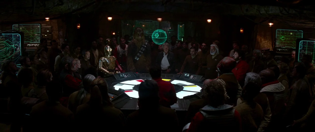 Star Wars: The Force Awakens (2015) movie still: wide — A dimly lit command center features a large circular tactical table emitting a green…