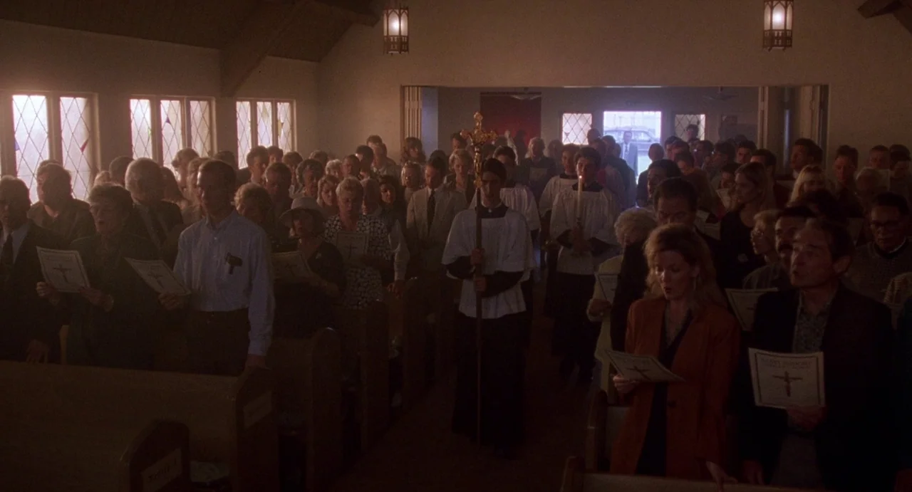 Touch (1997) movie still: wide — A crowded interior of a small church during a service with rows of wooden pews. Members of the congregation stand…