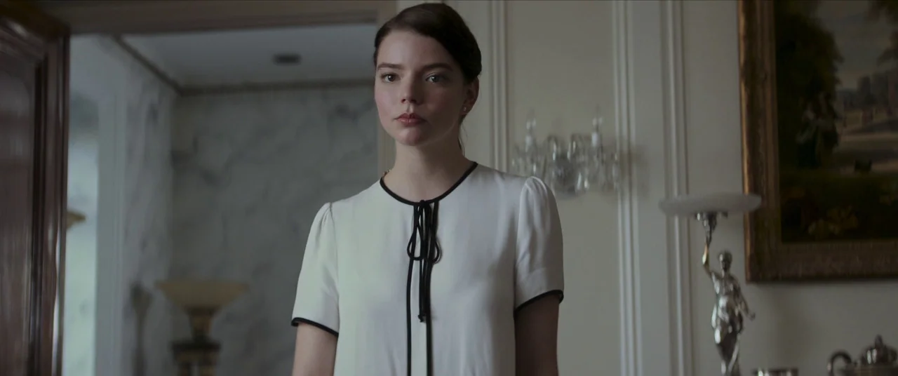 Thoroughbreds (2017) movie still: medium — An upscale corridor features white marble walls and a framed oil painting. A young woman in a cream…