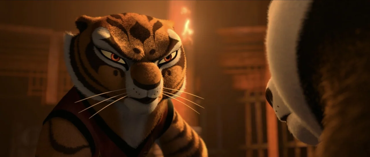 Kung Fu Panda 2 (2011) movie still: closeup — The interior of a dimly lit wooden building features warm firelight glowing nearby. A tigress…