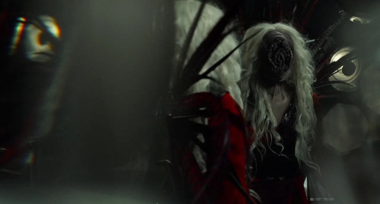 Rabid (2019) movie still: medium — A dimly lit room contains a mirror reflecting a creature with long white hair. The figure in the red garment…