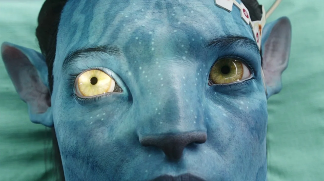 Avatar (2009) movie still: closeup — An alien with blue skin lies on a light green surface. A white medical sensor is attached to the subject's…