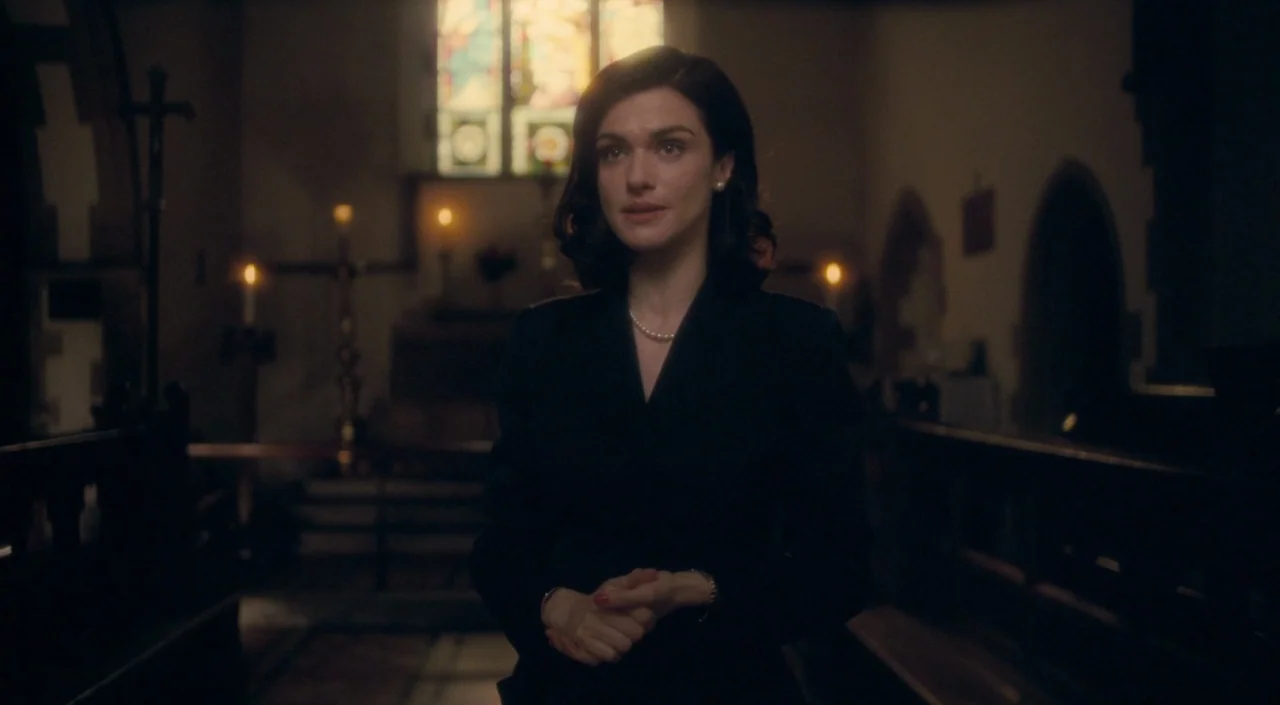 The Deep Blue Sea (2011) movie still: medium — A stone church interior features wooden pews and a lit stained glass window. A woman stands in the…