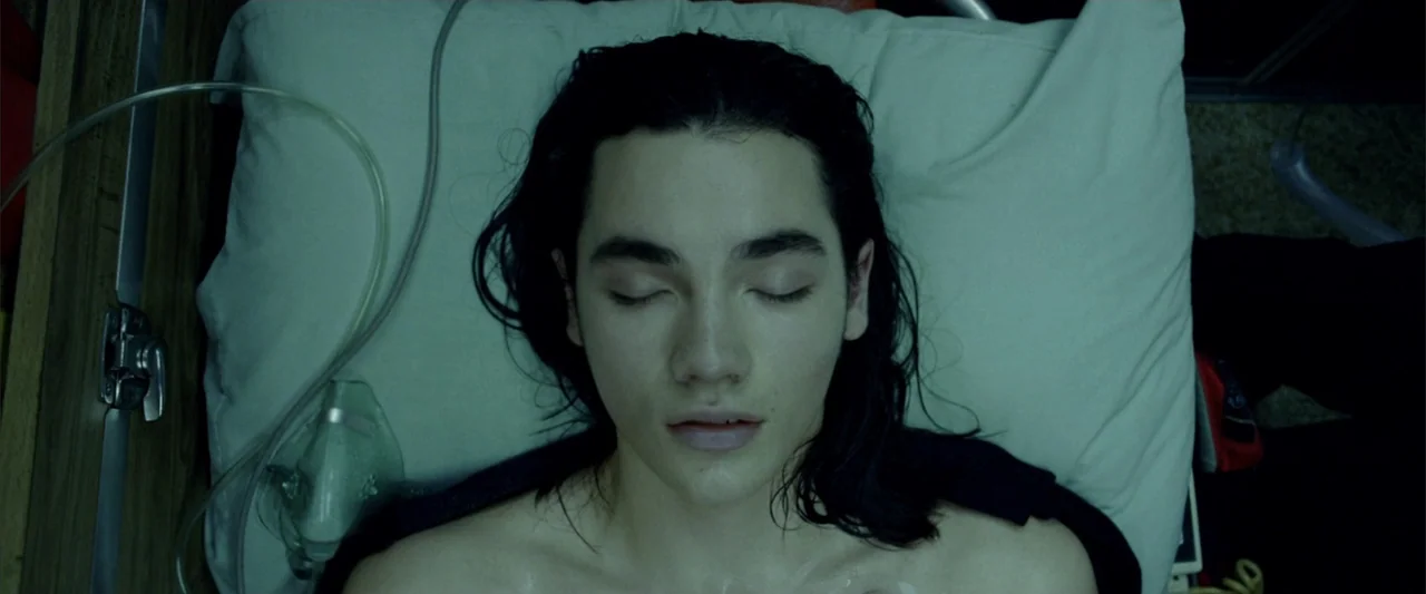 Constantine (2005) movie still: closeup — A top-down view of a hospital pillow and medical equipment headrest. A young male with long damp dark hair…
