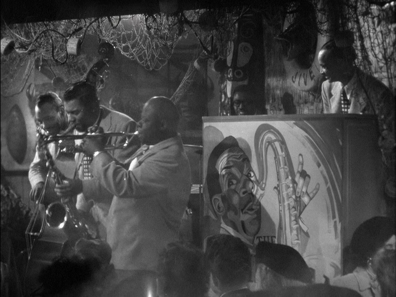 D.O.A. (1949) movie still: medium — A dimly lit club interior featuring a jazz band performing on a small stage. The musicians stand behind a large…