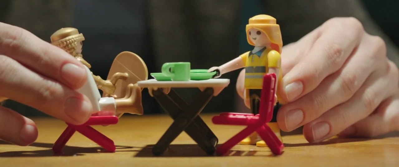 On Body and Soul (2017) movie still: closeup — Two human hands interact with small plastic figures sitting at a miniature folding table. The scene…