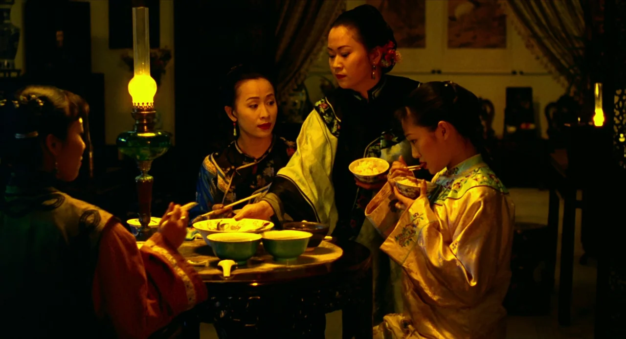 Flowers of Shanghai (1998) movie still: medium — A dimly lit room features three women sitting at a round dark wood table. They eat from ceramic…