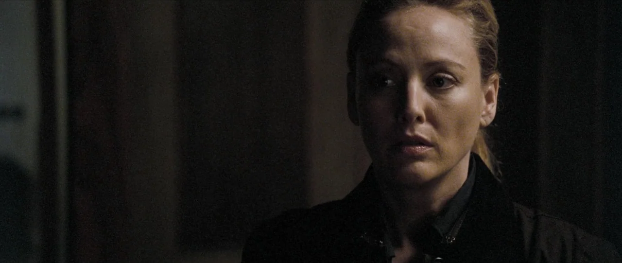 The Haunting in Connecticut (2009) movie still: closeup — A dark indoor setting features a woman positioned in the right side of the frame. The…