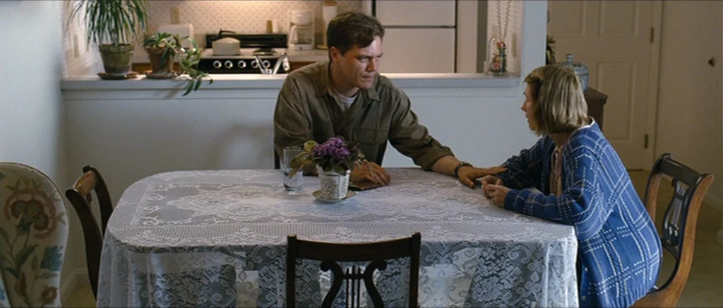Take Shelter (2011) movie still: medium — A man and a woman sit at a table covered by a white lace cloth. The man places his hand on the woman's…