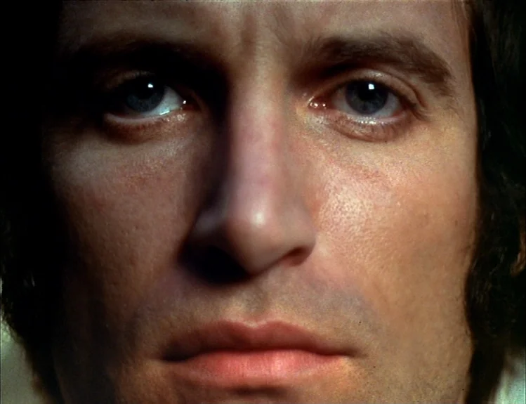 The Arrival of Joachim Stiller (1976) movie still: closeup — A close-up shot of a man's face against a dark, featureless background. The man stares…