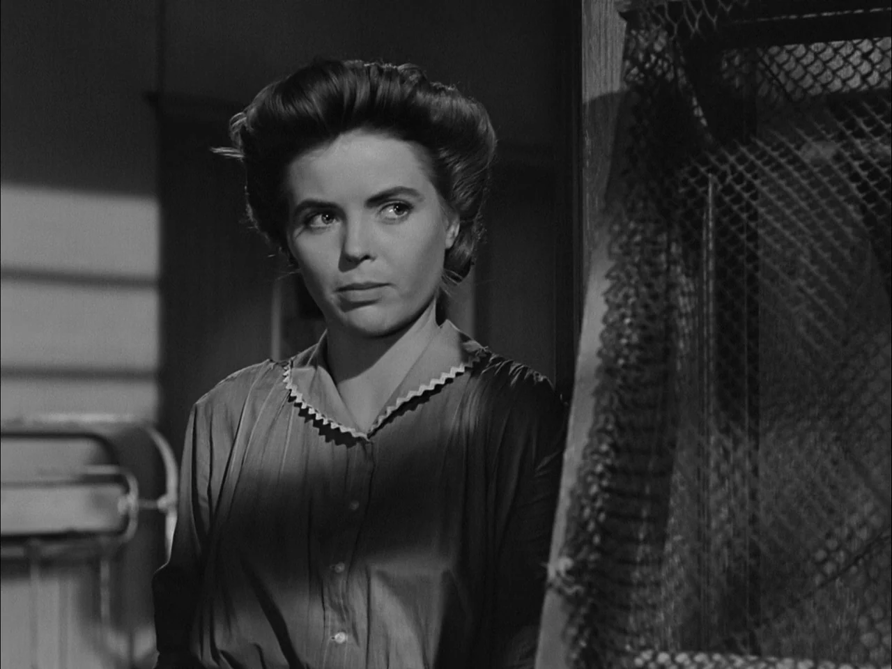 A Tree Grows In Brooklyn (1945) movie still: medium — A woman stands in a dimly lit interior space with a fishing net nearby. She is looking away…