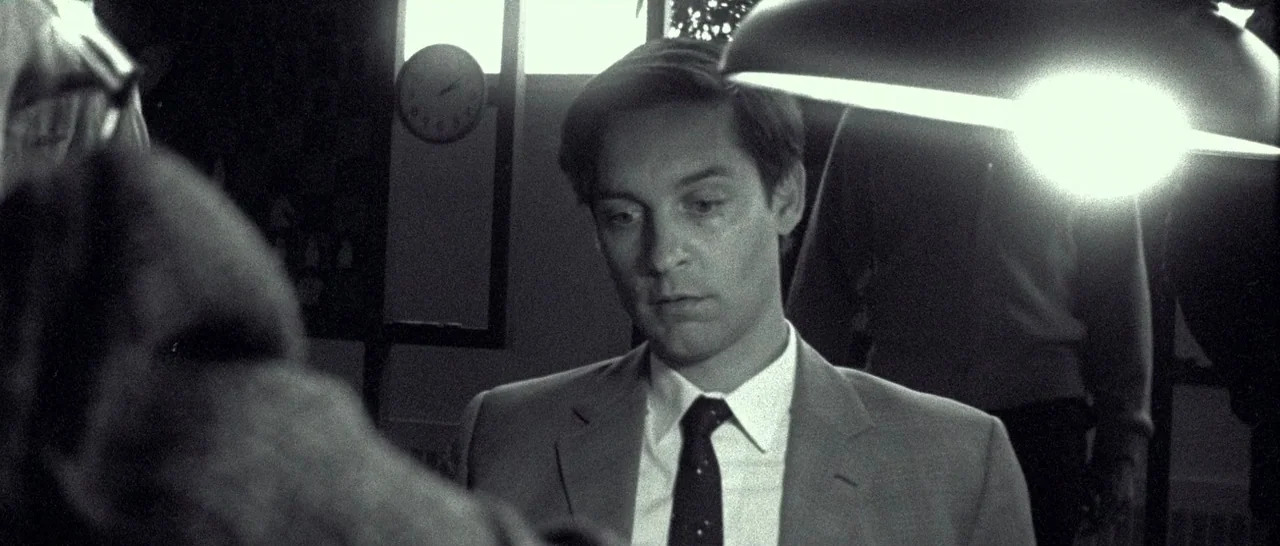 Pawn Sacrifice (2014) movie still: medium — A workspace environment features a circular clock hanging on a wall in the background. A man in a suit…