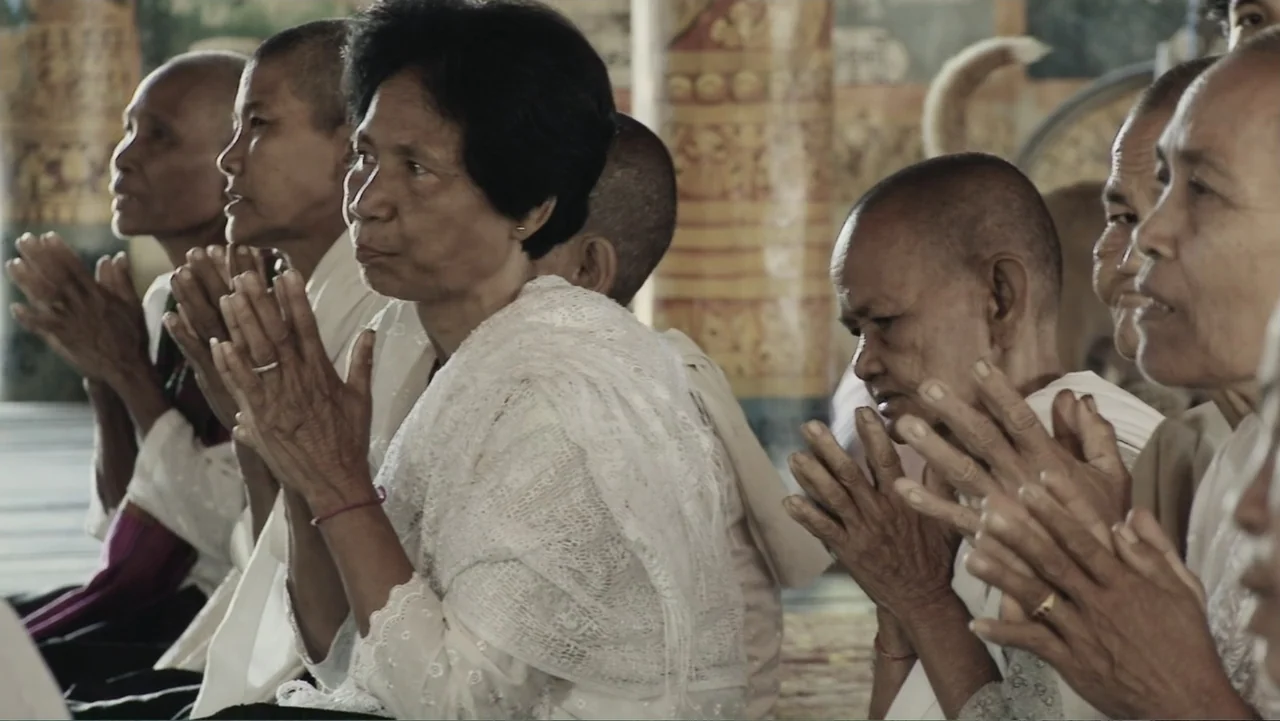 A Cambodian Spring (2018) movie still: medium — A group of women are seated within a building featuring decorated columns. They have their hands…