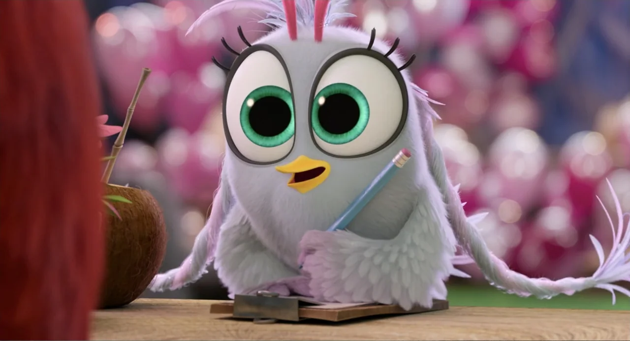 The Angry Birds Movie 2 (2019) movie still: medium — A light-furred bird sits at a wooden table in an outdoor setting. The character uses a blue…