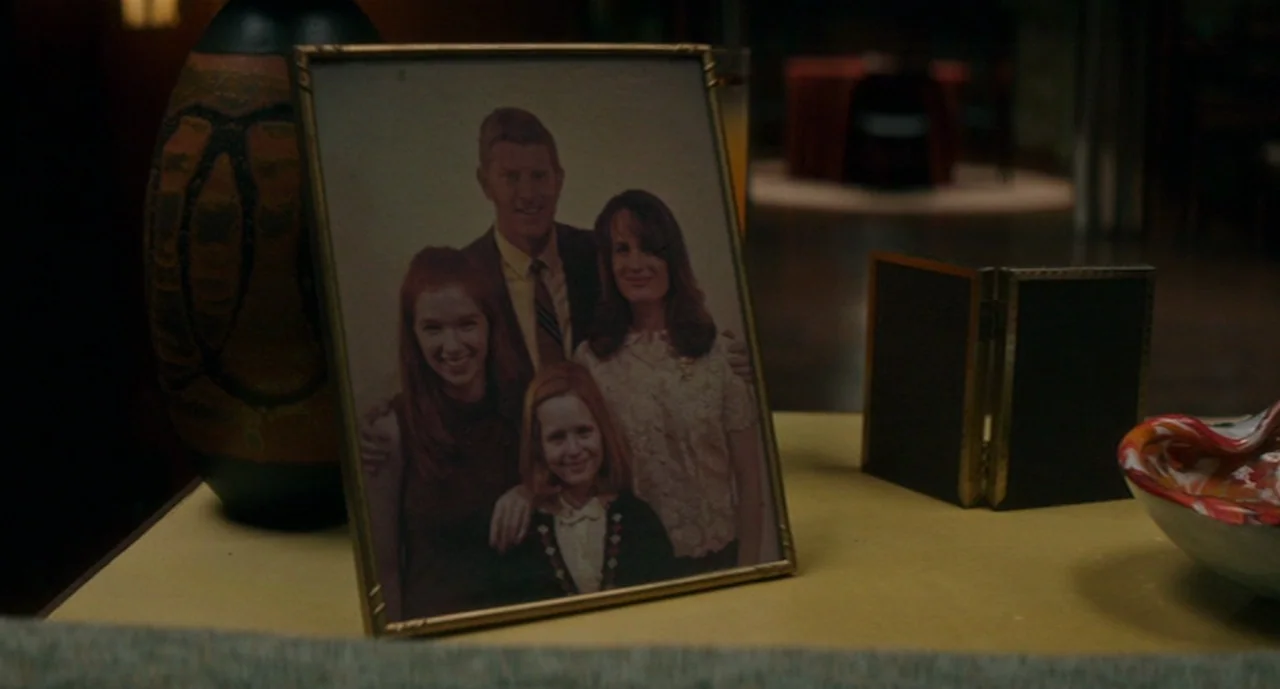 Ouija: Origin of Evil (2016) movie still: closeup — A dimly lit room features a photograph frame on a wooden surface. The photograph depicts a…