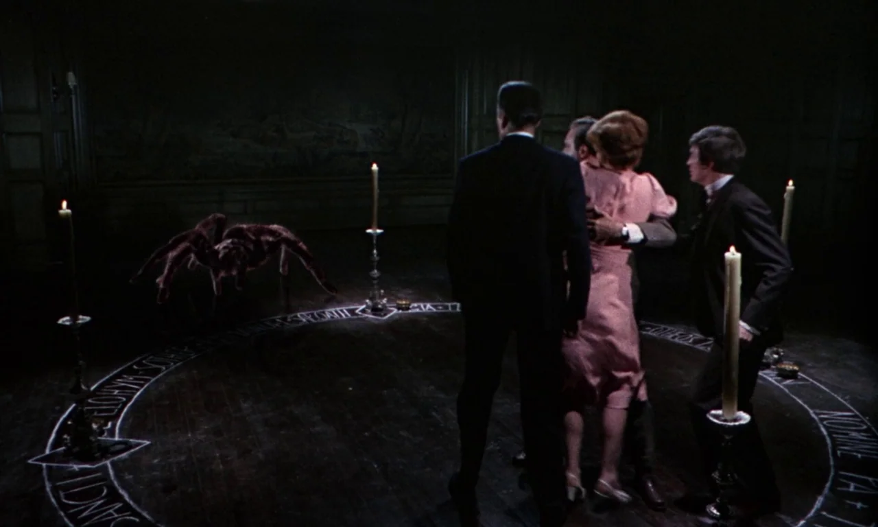The Devil Rides Out (1968) movie still: wide — A dark, wood-paneled room features a chalk circle drawn onto the wooden floorboards. Three people…