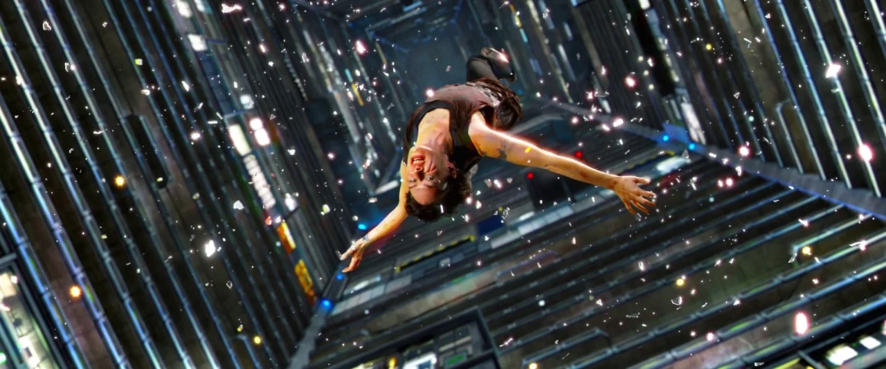 Dredd (2012) movie still: fullbody — A tall multi-story apartment building atrium features repetitive balconies and cold metal surfaces. A woman…