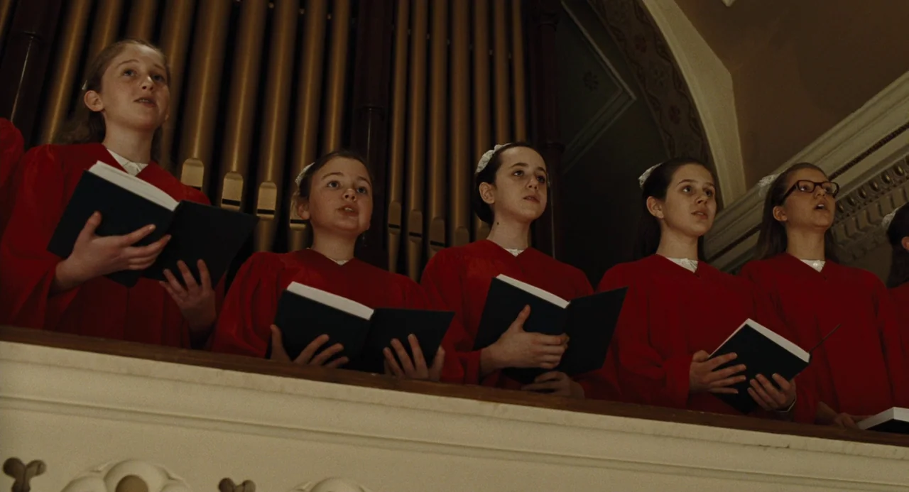 Doubt (2008) movie still: medium — A group of young girls stand in a choir loft before large organ pipes. They wear matching red robes and sing…