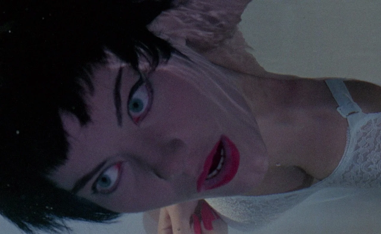 Blood And Black Lace (1964) movie still: closeup — A person is submerged beneath the surface of clear, light-filled water. The subject looks…