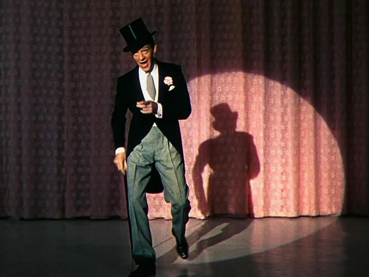 Ziegfeld Follies (1945) movie still: fullbody — A theatrical stage with a pink fabric curtain backdrop behind the male performer. The performer in a…