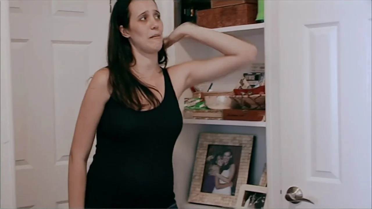 The (Dead Mothers) Club (2014) movie still: medium — A woman stands in front of white closet doors with shelves containing various small items. She…