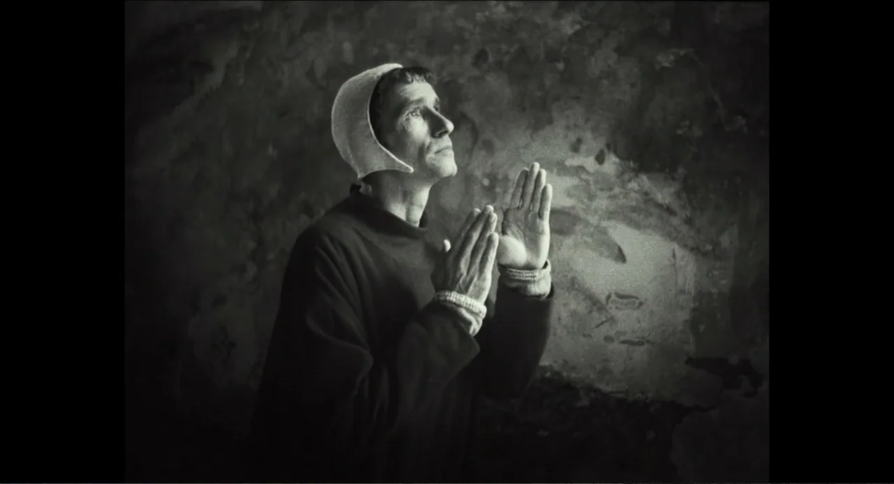 Pope Francis: A Man of His Word (2018) movie still: medium — A dark stone room with textured walls and faint weathered patterns. A man wearing a…