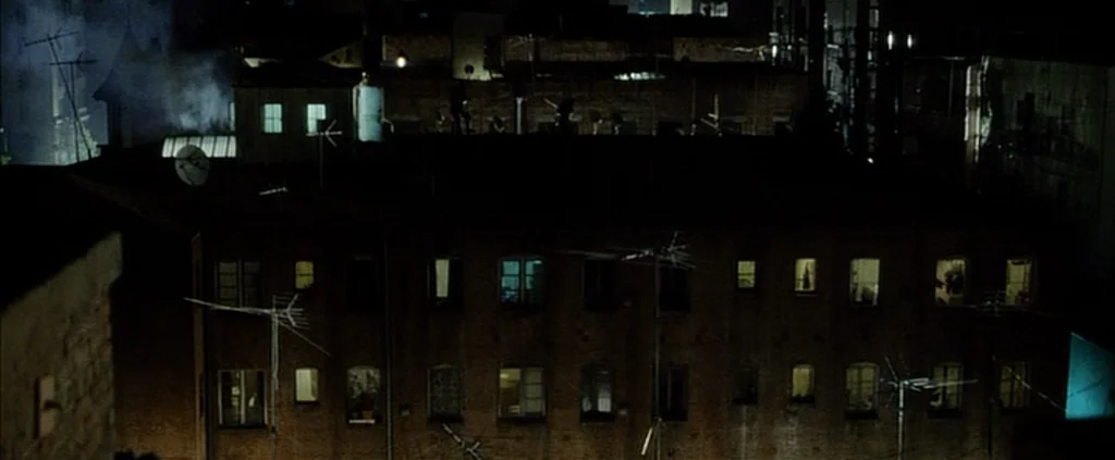 Fight Club (1999) movie still: establishing — A nighttime view looking across a series of dark urban residential apartment blocks. Multiple…
