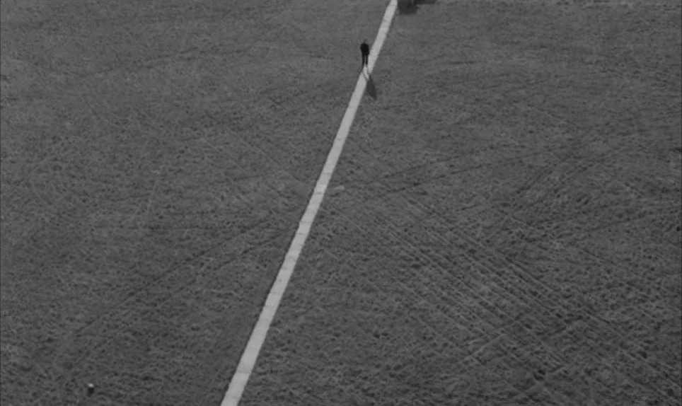 A Hard Days Night (1964) movie still: establishing — A vast, expansive field features a long, narrow concrete path leading into the distance. A…