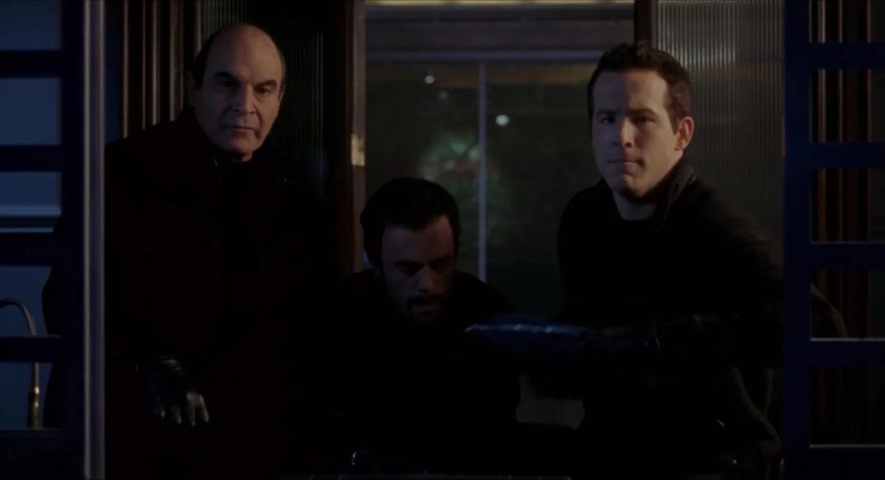 Foolproof (2003) movie still: medium — Three men stand in a dark, narrow hallway with door frames flanking them. The men are grouped together…